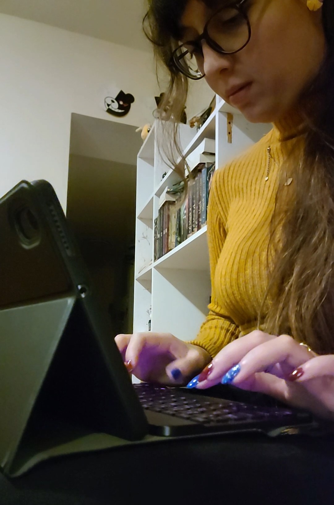 une femme au cheveux long et lunette qui tape sur un clavier